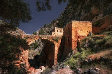 View of ruins of abandoned Katholiko monastery church on sunny Crete island. Beautiful mediterranean nature of Greece. Unique stone construction in the rock. Iconic ancient landmark