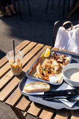Street food and a glass of coffee on a wooden outdoor table on a sunny day