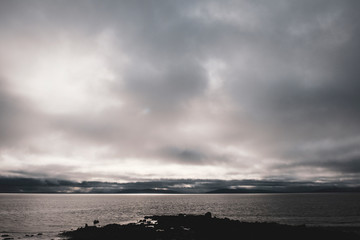Rocky coastline and views over Galway Bay to the Burren with rainclouds over the mountains