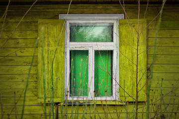 Window with wooden shutters. The old magical green window in the wall of ancient Latvian wooden house.