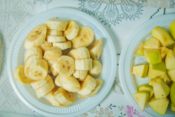 Cut banana in a plastic bowl. Banana slices in bowl over stone background with copy space. Healthy natural vitamin snack. Top view, flat . The chopped banana is in a plastic bowl .