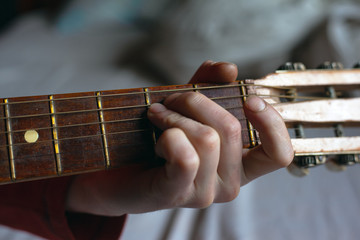 guy plays a melody on an acoustic guitar while holding his hand on the fretboard