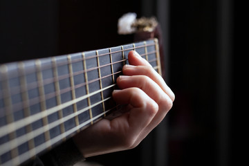 Female hand clamps a chord on an acoustic guitar