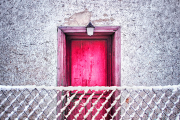 Pink door and white wall of old house in winter.