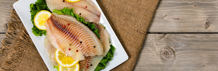 Whitefish Tilapia Fish Raw Fillet on Wooden Background. Selective focus.