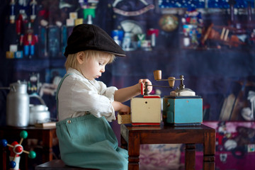 Little toddler boy, playing with mill at home, sitting on vintage table