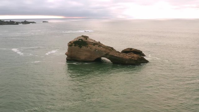 Drone shot circling the La Roche Percee, a prominent geologic feature 200m from the the coast and surfing beaches of Biarritz, France.