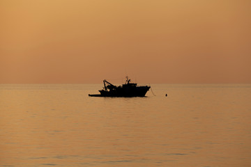 Fishing boat silhouette moored offshore (no people around)