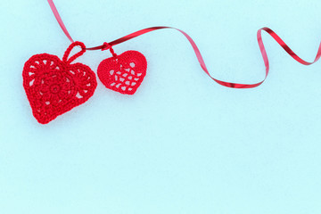 Crocheted red hearts with ribbon on snow. Valentines Day background.