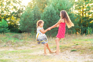 Two Happy cute  little girls embracing and dancing at sunny summer day outdoors