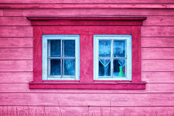  The two old magical pink windows in the wall of ancient Latvian wooden house.