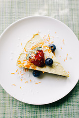 delicious slice of mango cake with berries on a white plate in a restaurant