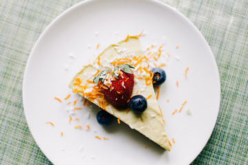 delicious slice of mango cake with berries on a white plate in a restaurant