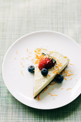 delicious slice of mango cake with berries on a white plate in a restaurant
