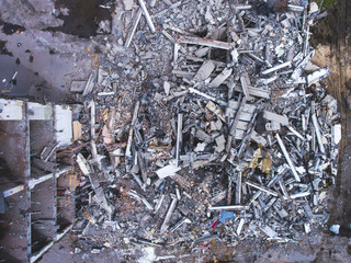 A process of buliding demolition, demolition site with heavy bulldozer and excavator with crushing equipment at work, demolished house, shot from air with drone