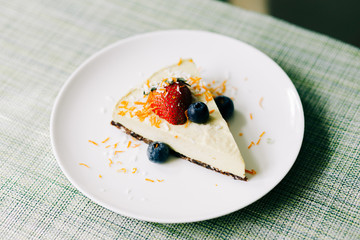 delicious slice of mango cake with berries on a white plate in a restaurant