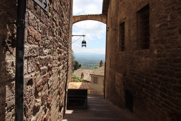 narrow street in old town of Assisi with scenic view in distance