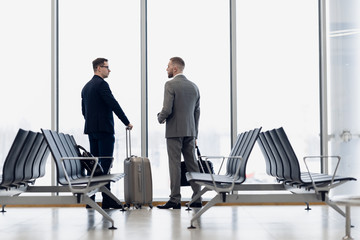 Business colleagues waiting at airport lounge standing and talking