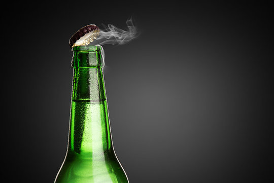 Cold wet bottle of chilled drink with drops. Opening of beer cap with the gas output.