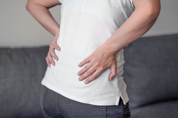 Woman suffer from low back pain. Hand of woman holding her waist backache in pain. Health care concept.