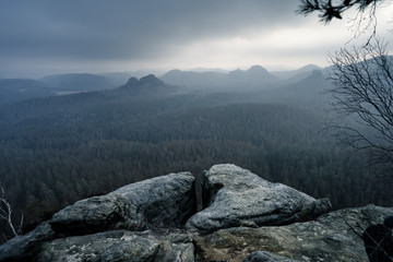 View into deep misty valley in Saxony Switzerland, Germany. Sandstone peaks and rocky hills