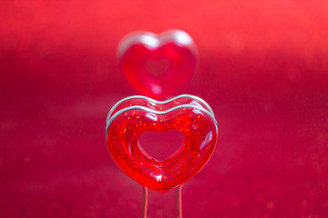 Two red hearts on a stand in the foreground on a red background with bokeh