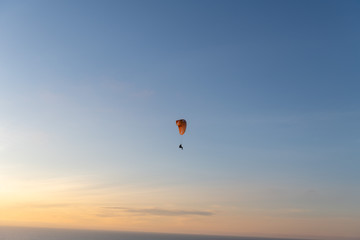Paraglider flying over thesea shore at sunset. Paragliding sport concept.