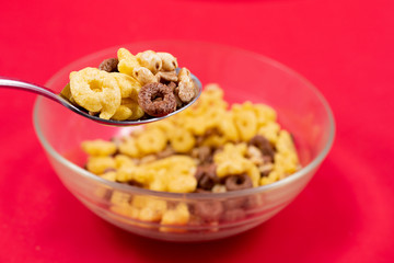 Cereals of different flavors with spoon on transparent bowl