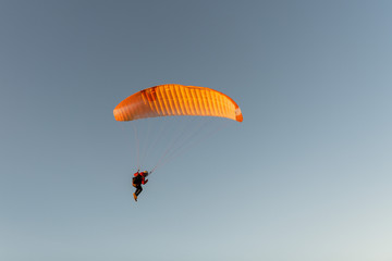 Paraglider flying over thesea shore at sunset. Paragliding sport concept.