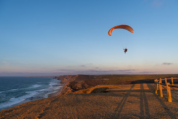 Paraglider flying over thesea shore at sunset. Paragliding sport concept.