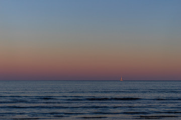 Naklejka na ściany i meble Dawn over the sea. Blue water, purple sky.