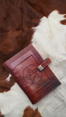 Vintage leather book with pentagram symbol laying on horse fur backgrounds