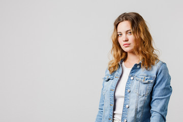 Candid young girl with long flowing hair in a denim looks calmly at the camera. Half-length...