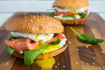 Burger with spinach, fish and eggs benedict, with a fresh roll with marzipan close-up against a brick wall with copy space