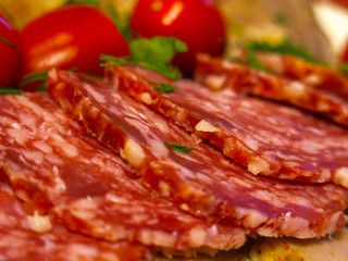 meat cuts for the festive table: salami sausage, boiled tongue, tomatoes and greens