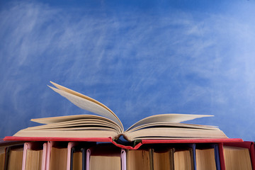 Education and reading concept - group of books on the wooden table, blue blackboard background. Teachers desk