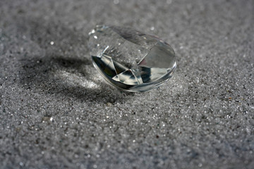Artificial diamonds lying in the sand photographed in the studio with flash light