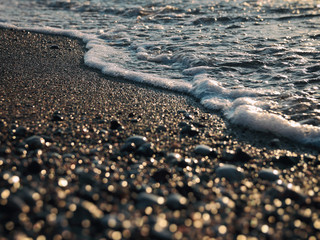 Fototapeta na wymiar Beach pebbles and foamy wave