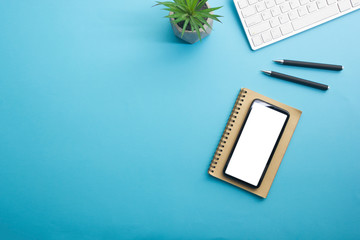 Blue desk office with laptop, smartphone and other work supplies with cup of coffee. Top view with...