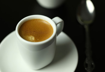 Concetto di bevanda italiana. Tazza bianca classica di caffè espresso con caffè su fondo nero. 