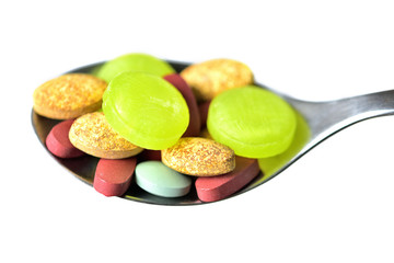 Close-up of spoon full of pills and tablets of vitamins, minerals, medicines and other dietary supplements isolated on white background