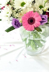 Wedding bouquet with pink and purple flowers on white tablecloth.