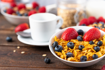hips with blueberries and raspberries in white bowl in dark wooden desk.