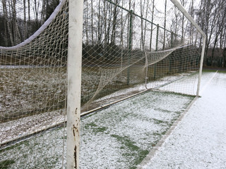 football goal with a grid close-up on a snow-covered sports field
