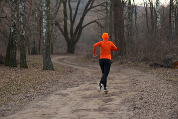 Beautiful sporty girl goes running in the forest Early spring