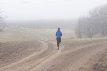 Young sporty girl goes running in the nature Beautiful foggy morning Moody atmosphere