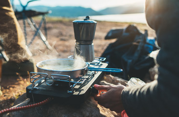 person cooking in nature camping outdoor, cooker prepare breakfast picnic on metal gas stove, hot...