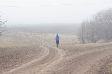 Young sporty girl goes running in the nature Beautiful foggy morning Moody atmosphere