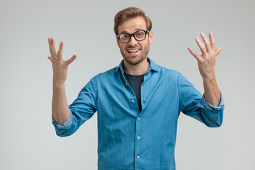 excited young casual guy holding arms in the air and celebrating