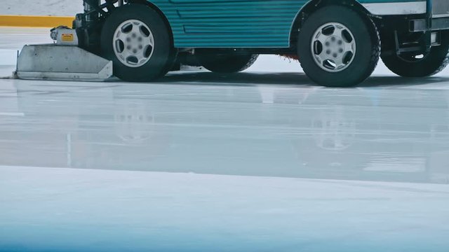 Zamboni resurfacing an indoor skating rink. Slow Motion. Ice resurfacer cleaning ice, machine cleaning and polishing smooth icerink. Ice harvester or restores ice.